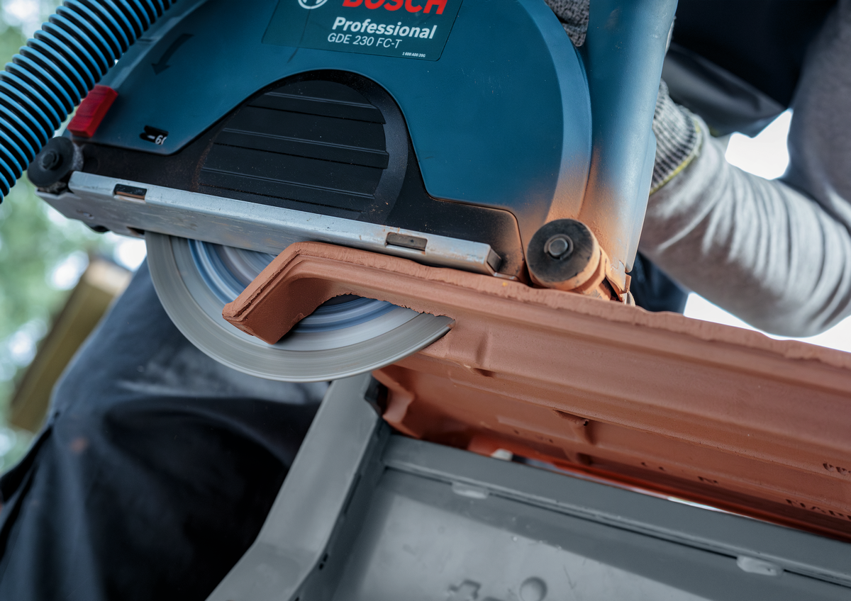 Bosch EXPERT MultiMaterial Diamond Cutting Disc 230mm actively cutting tile with visible motion blur on construction site.
