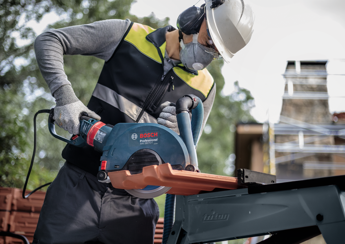 Professional cutting tile with Bosch EXPERT MultiMaterial Diamond Cutting Disc 230mm using Bosch grinder outdoors.