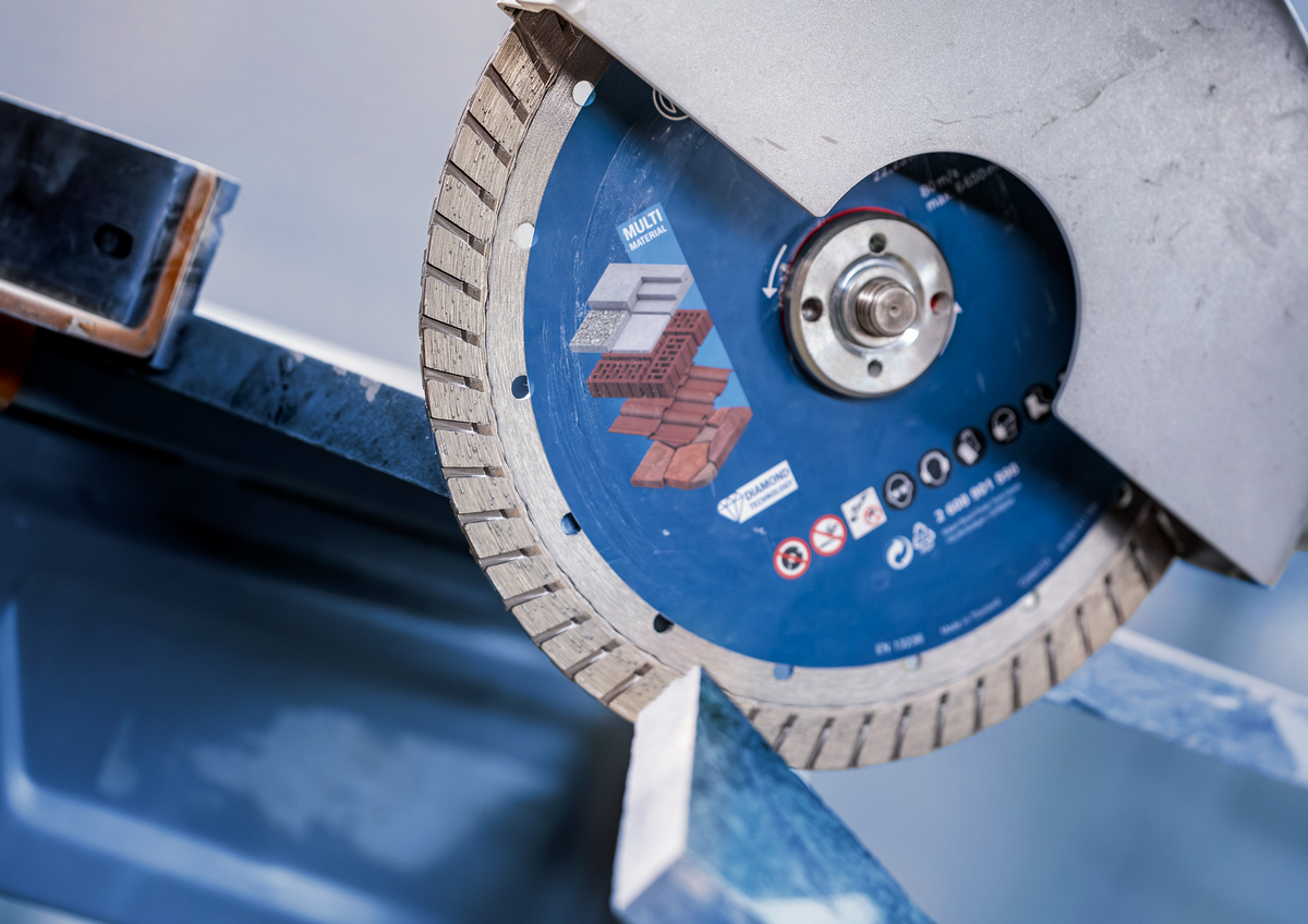 Bosch EXPERT MultiMaterial Diamond Cutting Disc 230mm cutting through metal with grinder in workshop setting.
