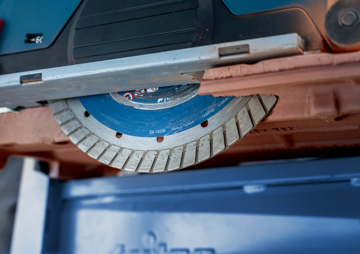 Close-up of Bosch EXPERT MultiMaterial Diamond Cutting Disc 230mm mounted on a grinder cutting through ceramic tile.
