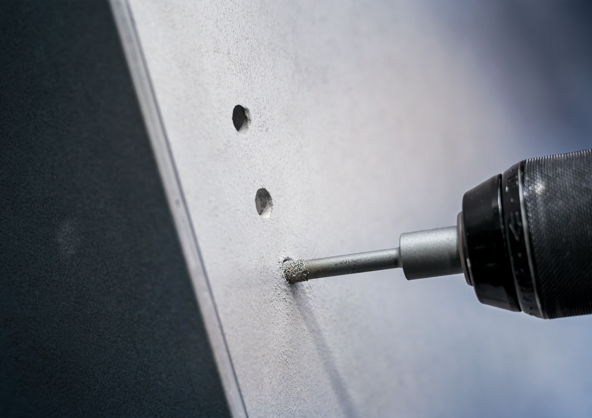 Close-up of Bosch PRO Ceramic dry Drill Bit creating hole in ceramic tile, emphasizing clean, dry drilling without cracking the surface.