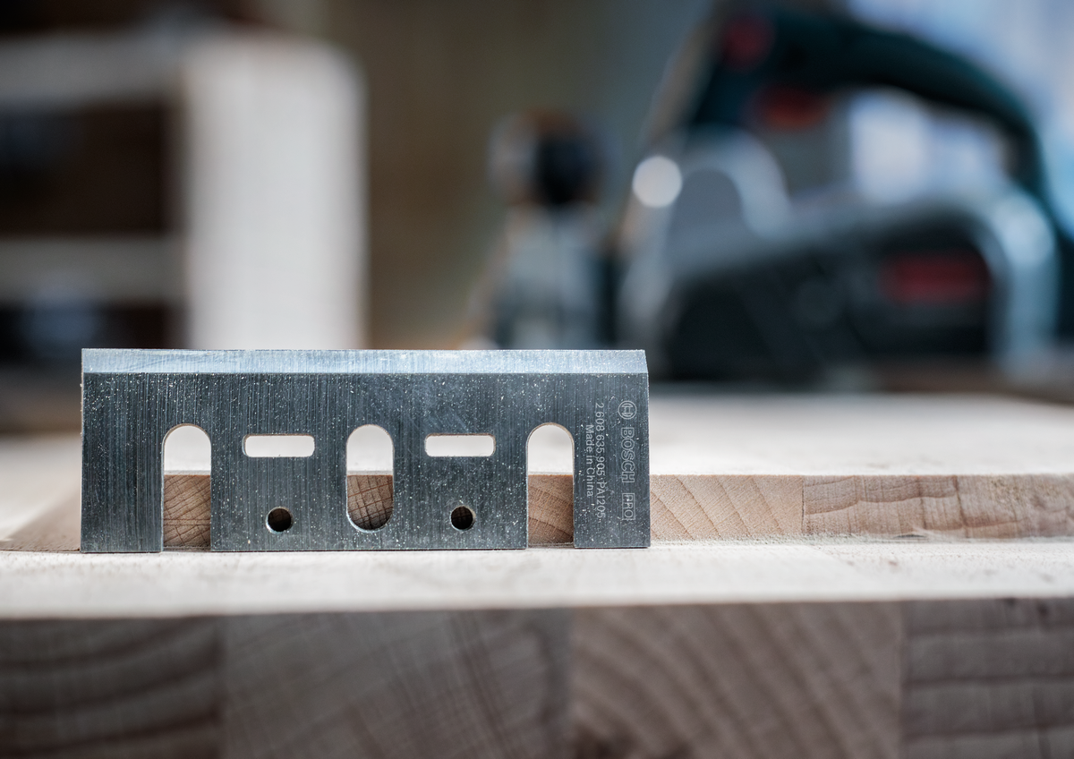 Bosch PRO Planer Knife, 82 x 29 x 3 mm 2608635905 standing upright on wood, emphasizing blade thickness and precision engineering.