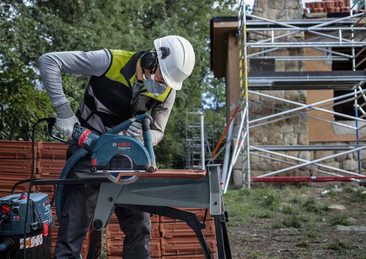 Bosch EXPERT MultiMaterial Diamond Cutting Disc 230mm in use on a tile by a professional worker at a job site.