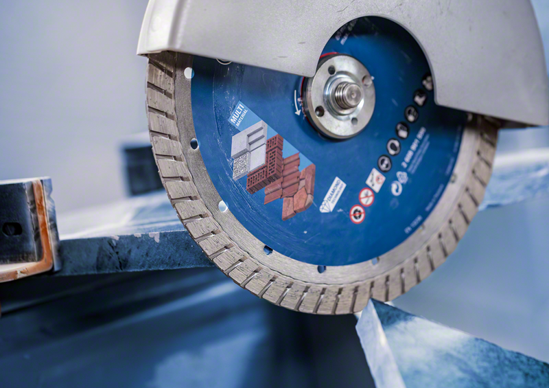 Close-up of Bosch EXPERT MultiMaterial Diamond Cutting Disc 230mm cutting metal with turbo rim visible.