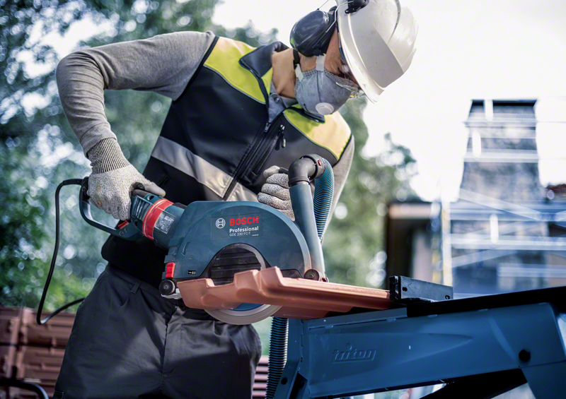 Worker using Bosch EXPERT MultiMaterial Diamond Cutting Disc 230mm with angle grinder to cut tile on construction site.