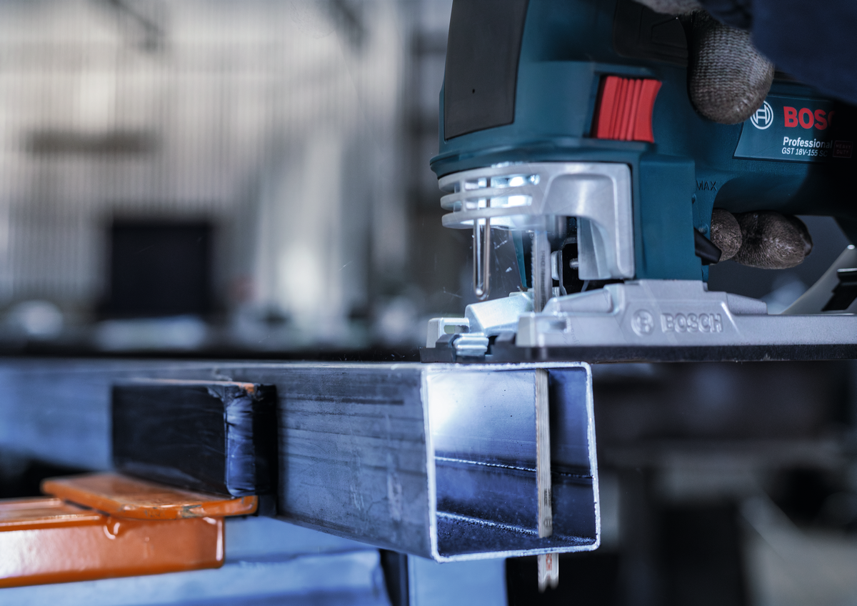 Close-up of Bosch jigsaw with T321BF blade slicing through a thick metal profile, demonstrating blade strength and accuracy.