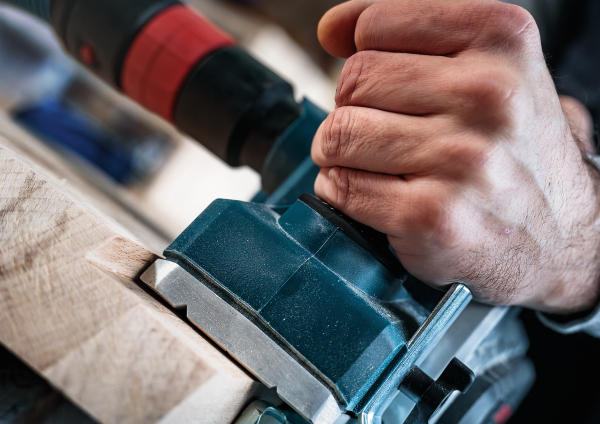 User securing Bosch PRO Planer Knife, 82 x 29 x 3 mm 2608635905 into electric planer, showing tool compatibility and ergonomic handling.