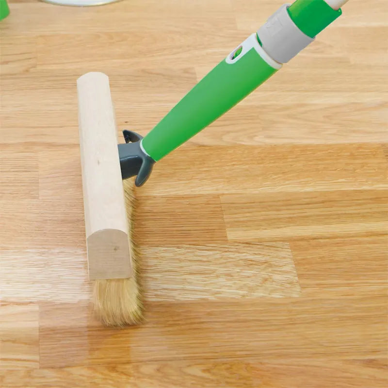 Osmo floor brush applying hardwax oil along the grain of an oak floor